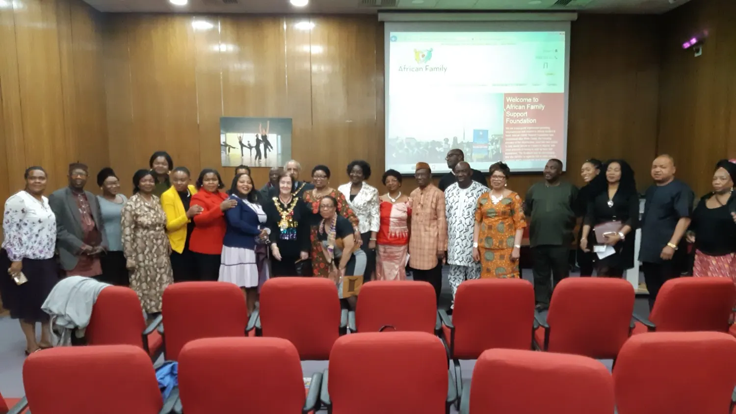 A group of staff and volunteers standing together in front of a Summer Gala Event banner.
